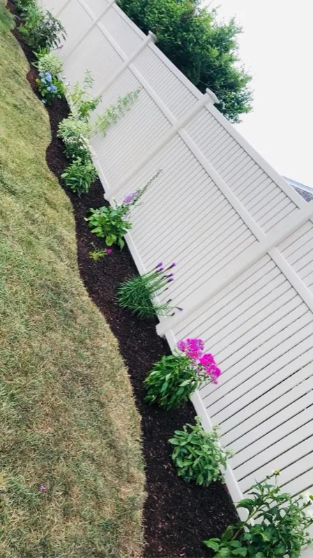Flower bed with mulch along fence